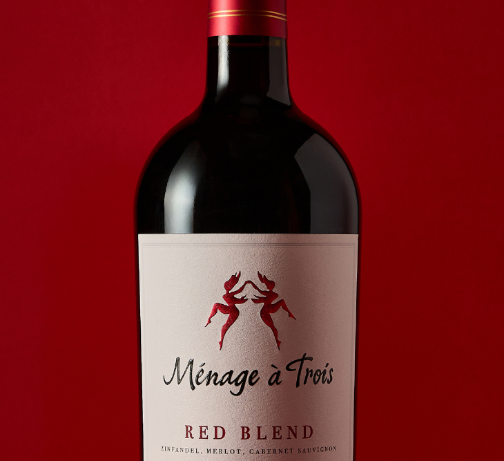 Bottle of Ménage à Trois Red Blend against a red background