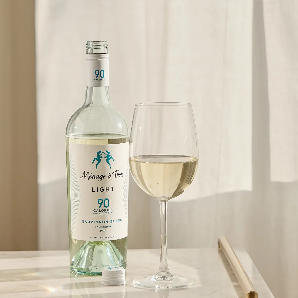Bottle and glass of Ménage à Trois Light Sauvignon Blanc white wine on a marble countertop